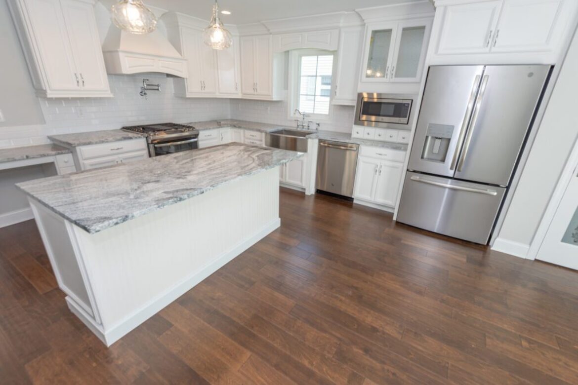White kitchen with granite island and hardwood floors.