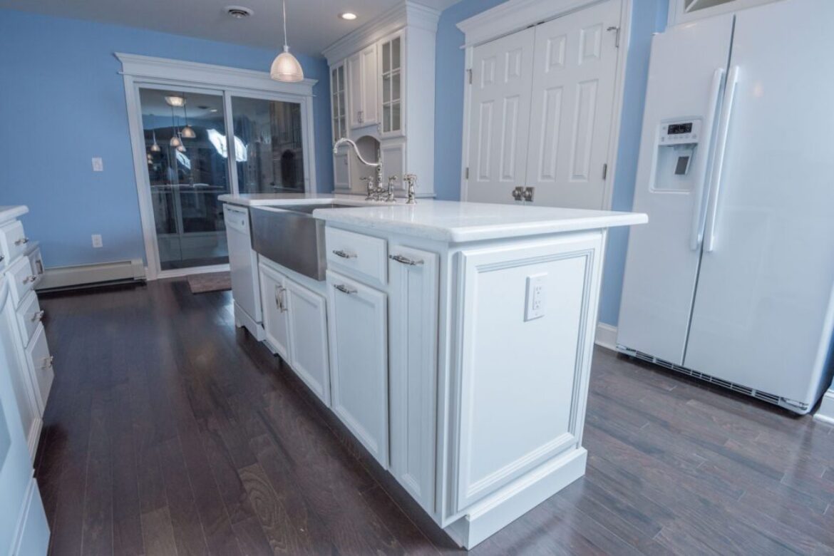 White kitchen island with stainless steel sink.