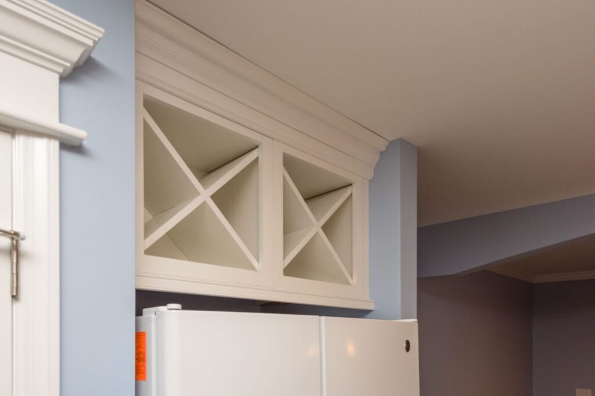 White cabinet above refrigerator with shelves.