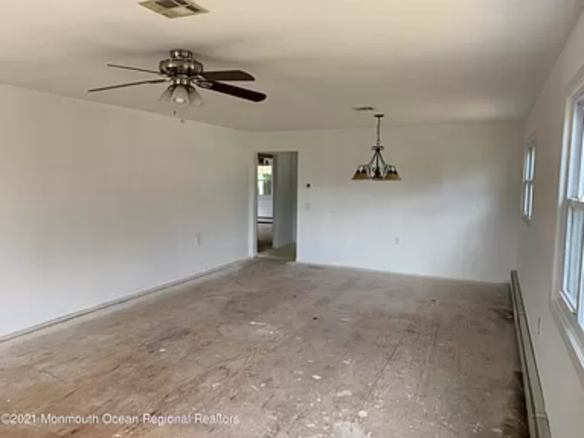 Empty living room with white walls and ceiling fan.