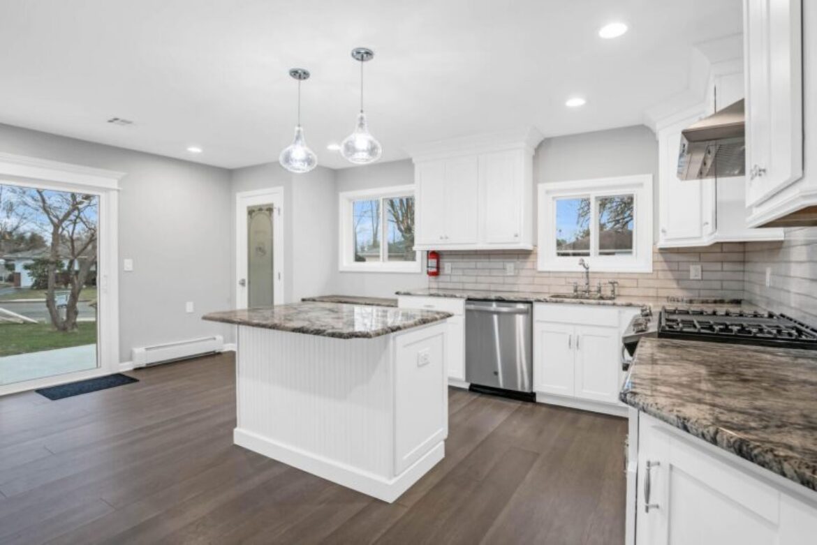 Modern white kitchen with granite countertops.