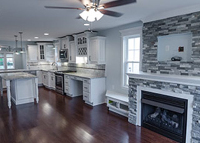 White kitchen with a fireplace and stone wall.