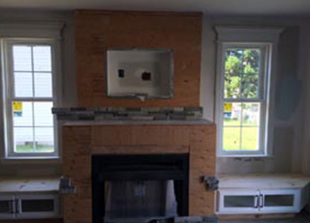 Fireplace with stone surround and windows.