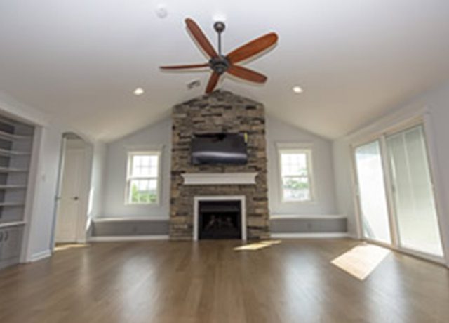 Modern living room with fireplace and ceiling fan.