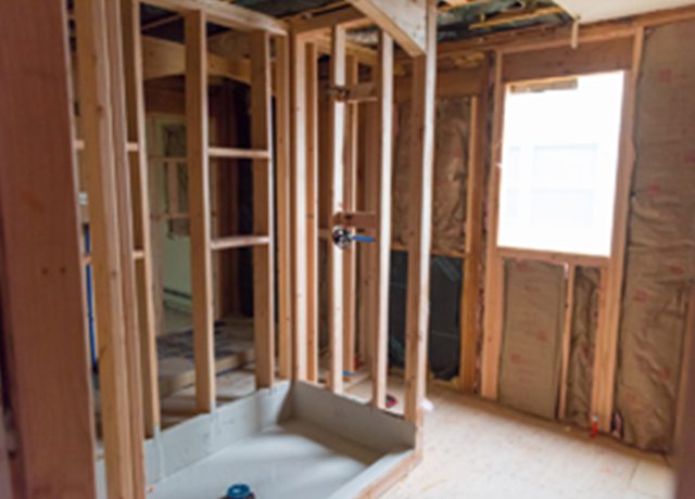 Unfinished bathroom with shower stall and window.