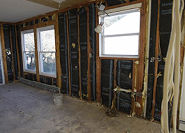 Unfinished room with two windows and exposed framing.