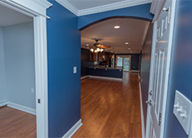 Blue hallway with doorway and hardwood floor.