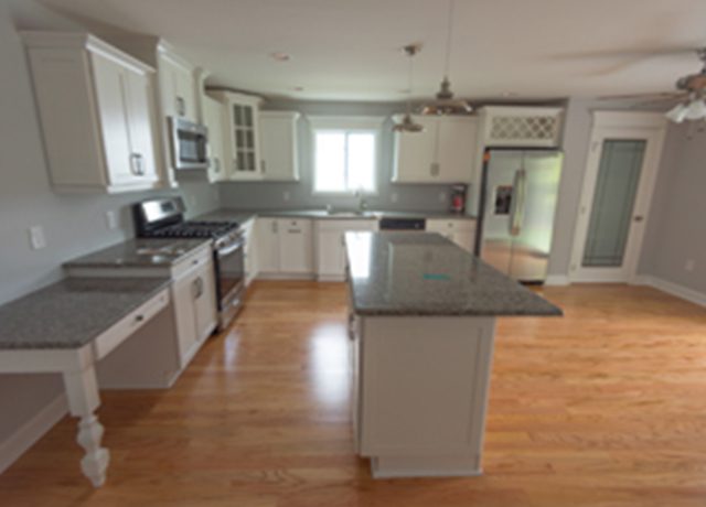 White kitchen with granite countertop and island.