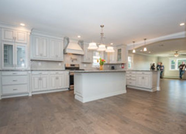 White kitchen with hardwood floors and island.