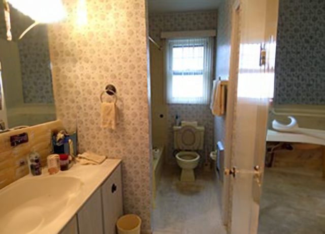 Bathroom with toilet, sink, and patterned walls.