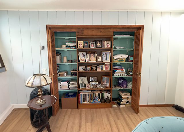 Wooden bookcase with family photos and books.