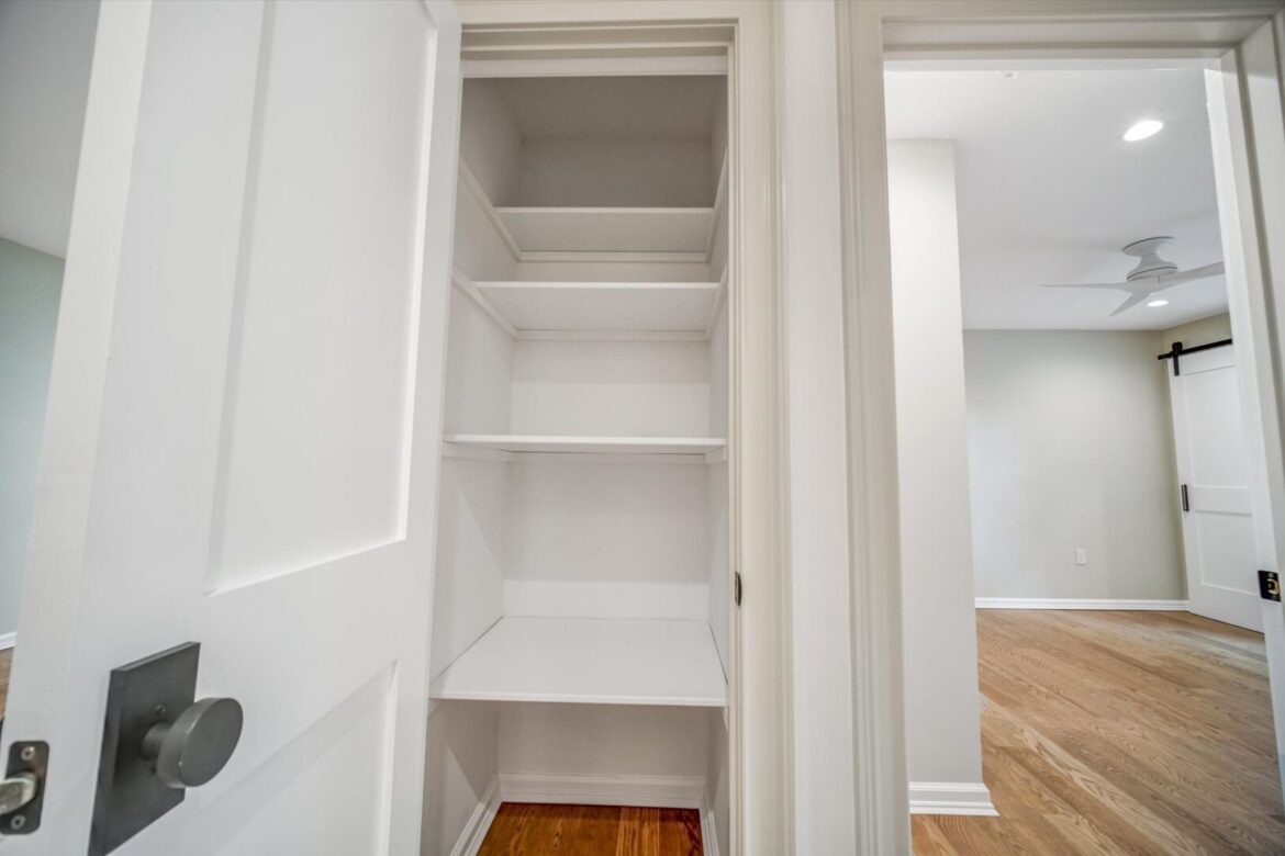 Empty closet with white shelves and door.
