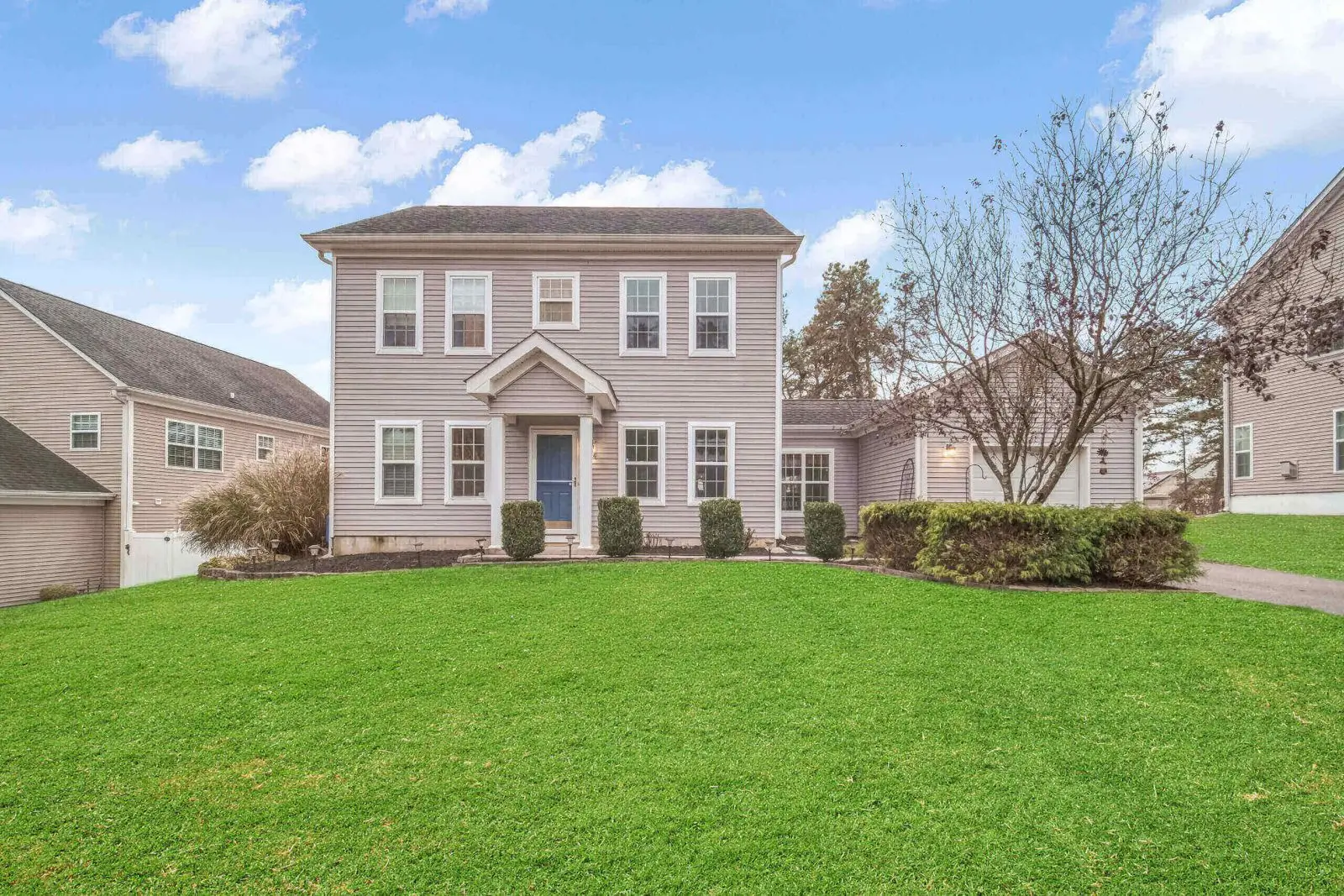 Two-story house with green lawn and trees.